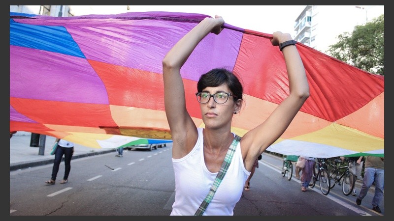 Una joven sostiene una enorme bandera multicolor en plena avenida Pellegrini. 