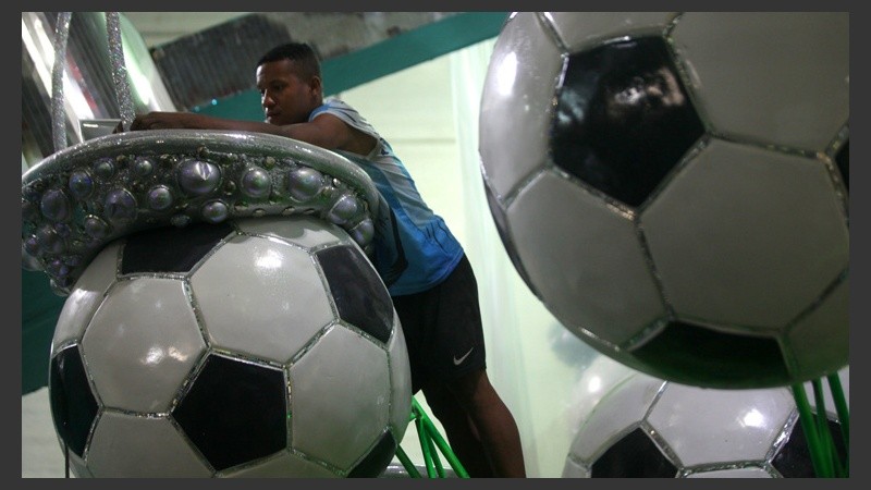 Un hombre trabaja sobre unos balones enormes de fútbol.