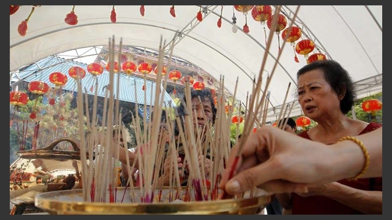 Mujeres encienden varillas de incienso a las puertas de un templo chino.