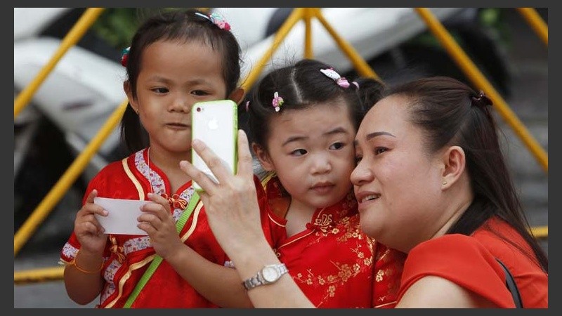 Una tailandesa de origen chino se toman una foto con dos niñas vestidas con el traje tradicional chino en la víspera de celebración.