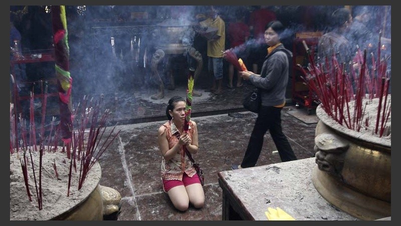 Una mujer en Indonesia de origen chino reza en las puertas de un templo.