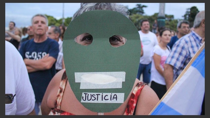 Una mujer pide justicia detrás de una máscara.
