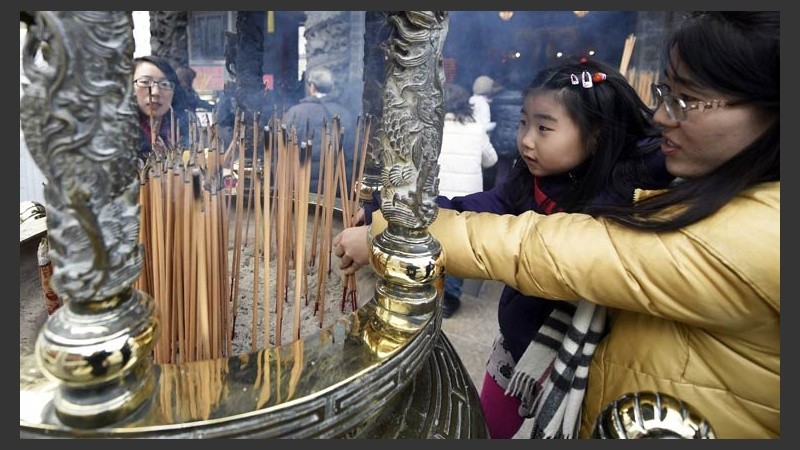 Una mujer y su hija encienden palos de incienso en el templo de Kanteibyo.