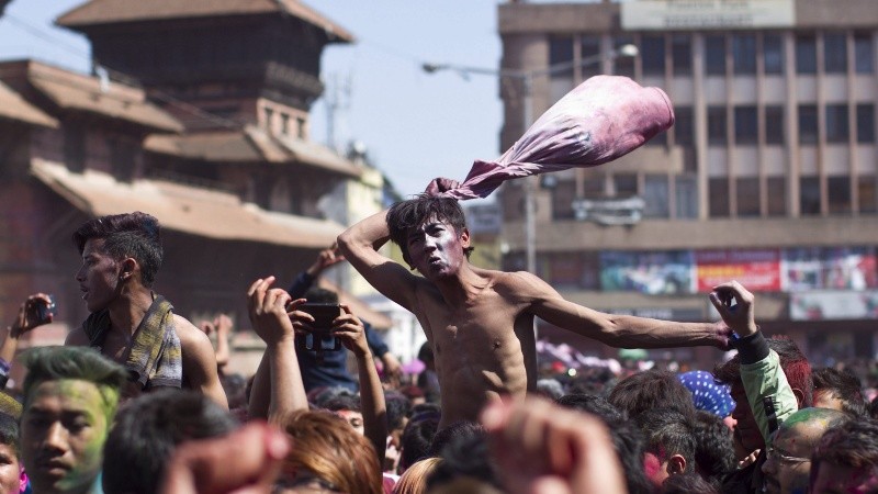 Varios nepaleses lcon los rostros manchados de polvos de colores bailan mientras participan en el Festival.