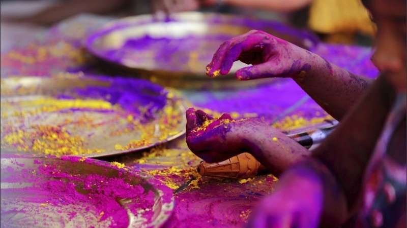 Varios niños toman polvos de colores para arrojárselos los unos a los otros mientras disfrutan del Festival.