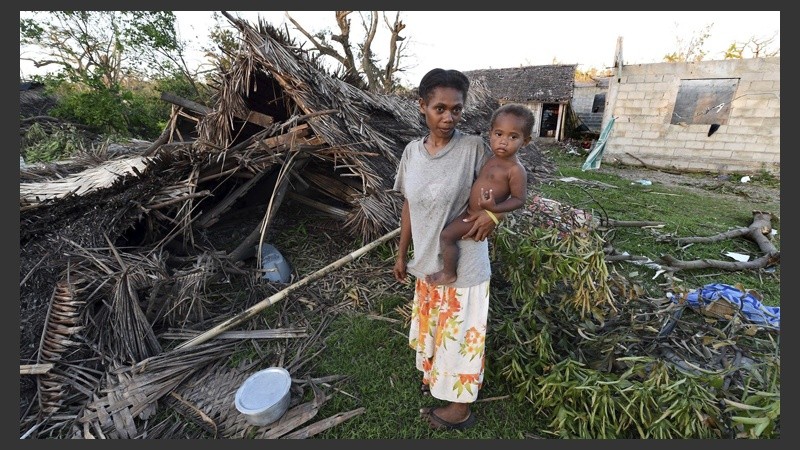 Lana Silona sostiene en brazos a su hijo Costello junto a las ruinas de su casa en la isla de Tanna en Vanuatu.