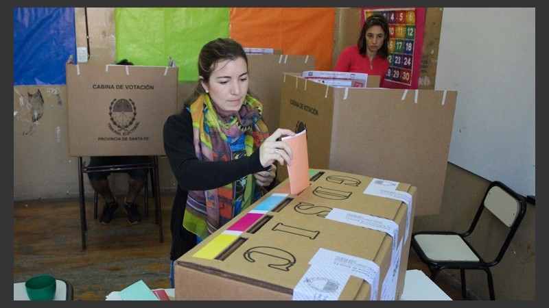 Una joven mete sus votos de colores en la urna.