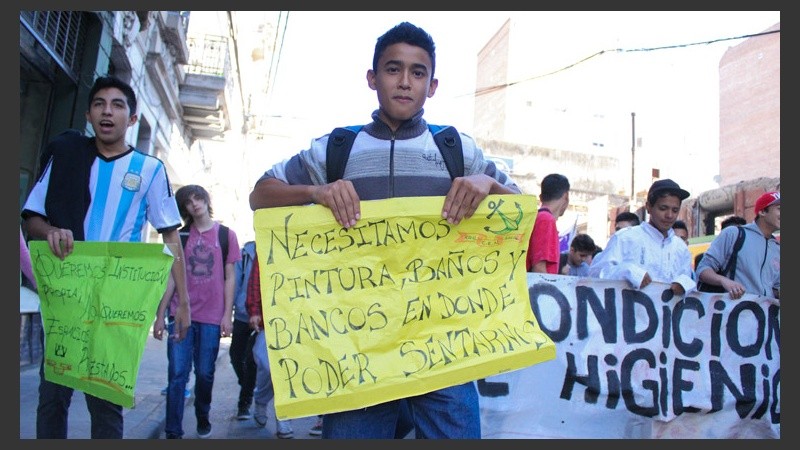 Un chico muestra un cartel reclamando mejoras.