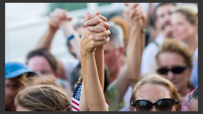 Dos mujeres toman fuerza agarrandose de las manos en una marcha en Charleston.