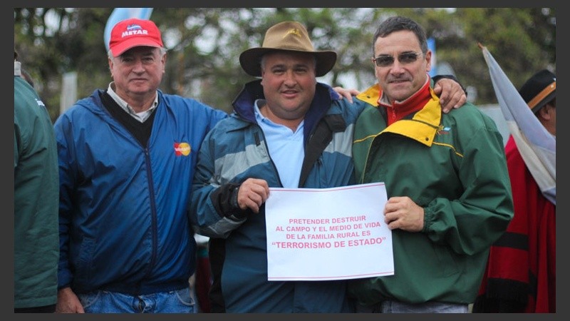 Un grupo de chacareros muestra uno de los carteles visto en la manifestación. (Alan Monzón/Rosario3.com)
