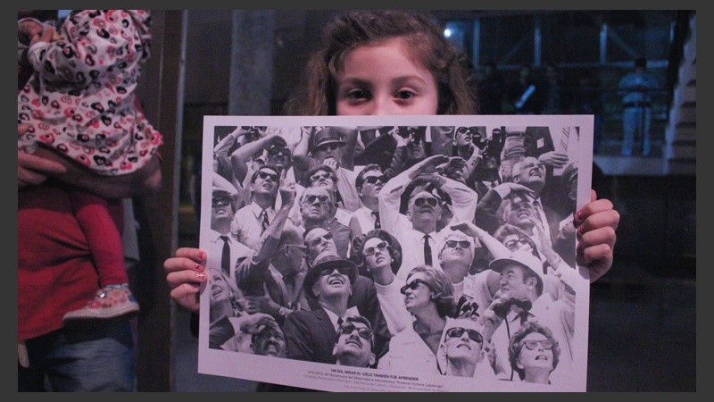 Una niña muestra uno de los afiches que los organizadores repartían en la jornada de observación. (Rosario3.com)