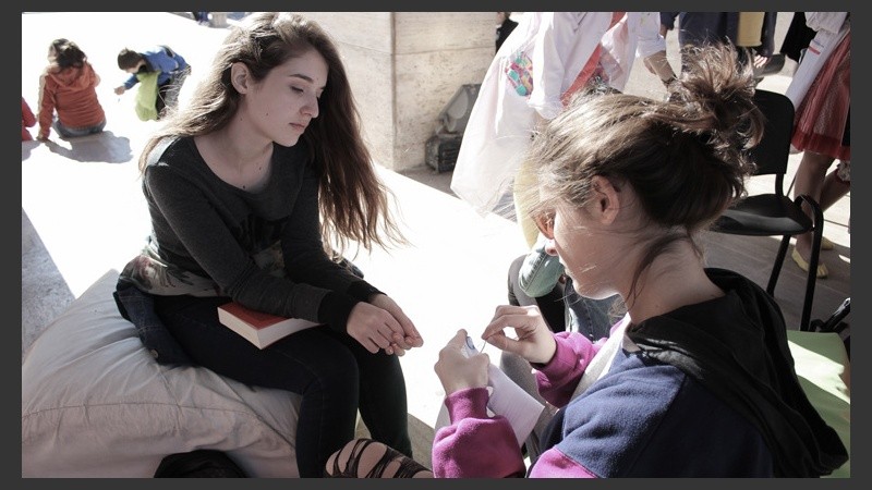 Una chica observa el trabajo de su compañera en una jornada soleada en el Monumento este sábado. (Alan Monzón/Rosario3.com)