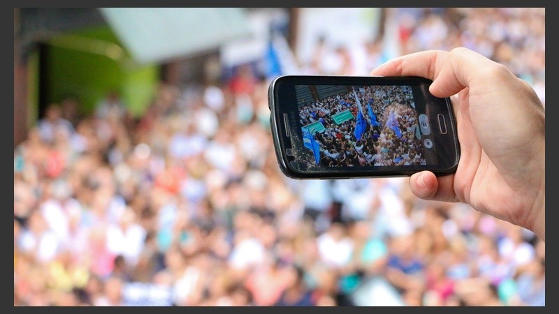 Un joven apunta su celular a la multitud para tomar una fotografía. (Alan Monzón/Rosario3.com)