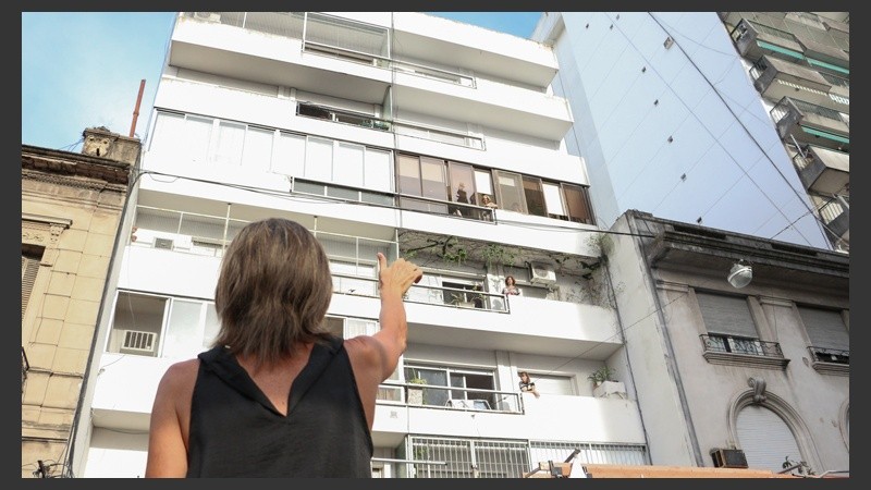 Una mujer se comunica con señas y gritos con su pariente en el edificio.