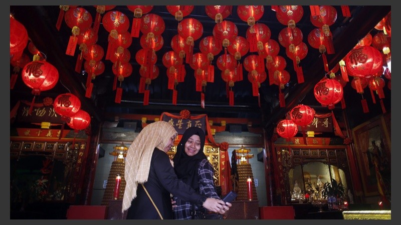 Dos mujeres indonesias posan para un selfie en el interior de un templo decorado con farolitos en la previa de los festejos. (EFE)