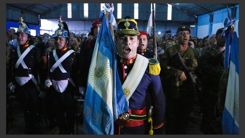 Un granadero porta la bandera frente al escenario.