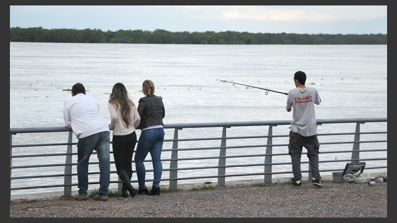 Tres curiosos observan los movimientos de uno de los pescadores. (Alan Monzón/Rosario3.com)