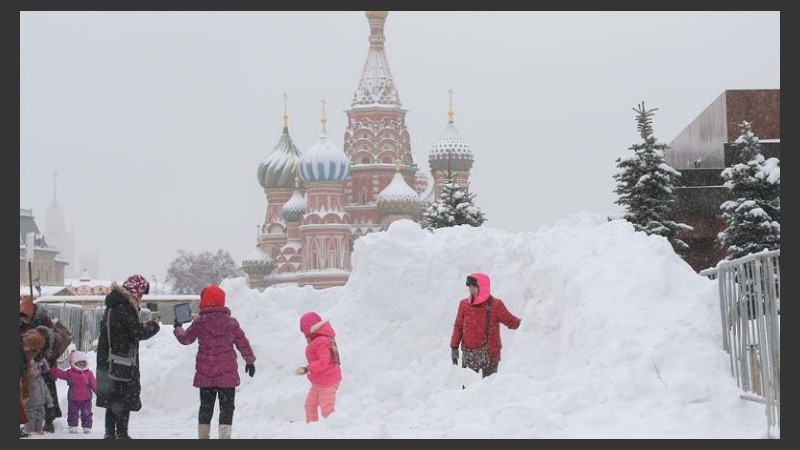 Un grupo de chicos juegan con nieve frente a la Catedral San Basilio de Moscú.