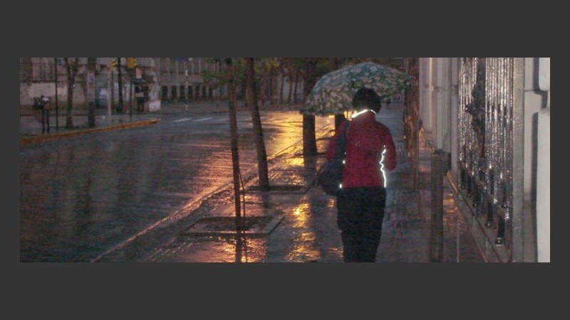 Mujer con paraguas rumba al inicio de otra jornada laboral.