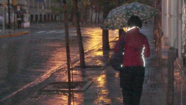 Mujer con paraguas rumba al inicio de otra jornada laboral.