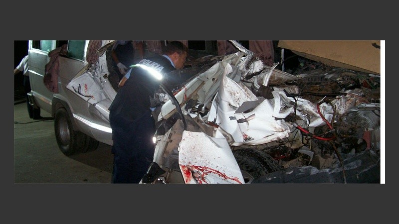 Un policía observa los restos de la combi (Federal al día).
