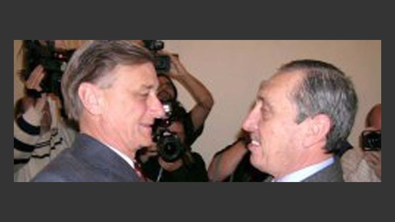 El gobernador electo y el saliente sonríen juntos para la foto.