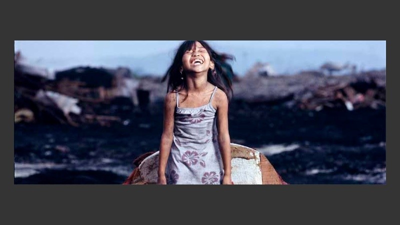 Annalyn, una nena de Manila, muestra su felicidad sobre un sillón en pleno basural.