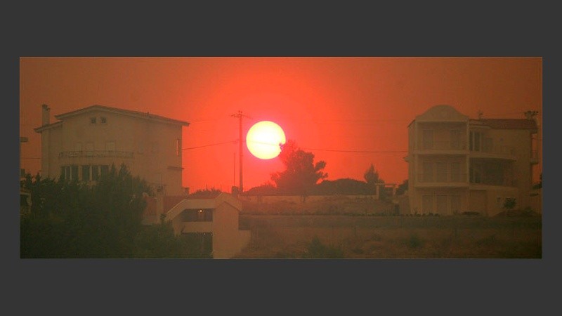 El sol se oculta tras una nube de humo de los incendios que arrasan las afueras de Atenas.