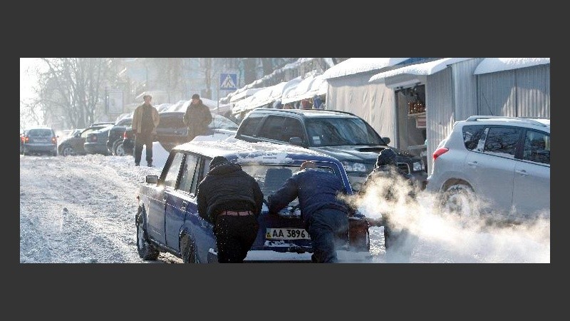Dos hombres empujan un auto que quedó varado en Ucrania. 