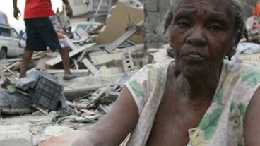 Una mujer haitiana sentada sobre las ruinas de su casa