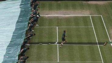 Operarios despliegan una lona para tapar la cancha.