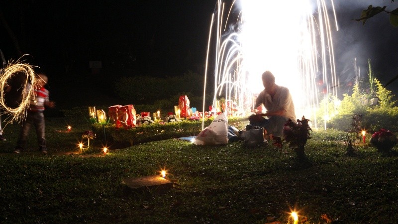 Una familia enciende velas junto a una tumba durante la 