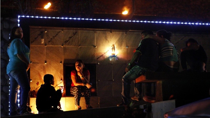 Una familia enciende velas junto a una tumba durante la 