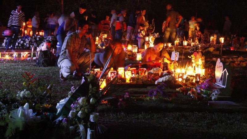 Una familia enciende velas junto a una tumba durante la 