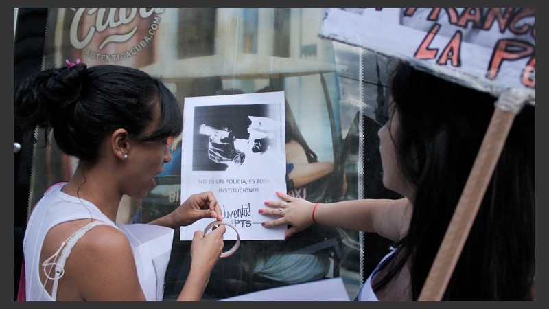 Dos chichas pegan un afiche en una de las paradas de colectivos. 