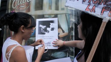 Dos chichas pegan un afiche en una de las paradas de colectivos.