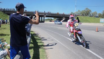 Un joven saca una fotografía en pleno saludo del motociclista.