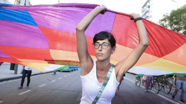 Una joven sostiene una enorme bandera multicolor en plena avenida Pellegrini.
