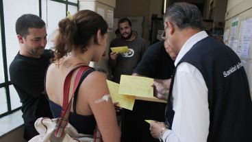 Un hombre le entrega el certificado internacional de vacunación a una joven a punto de viajar a Brasil.