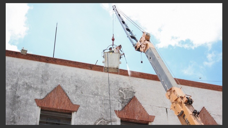 Unos operarios limpian la fachada con una hidrolavadora.
