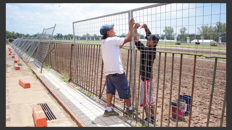 Bajo un intenso calor, dos jóvenes colocan una de las rejas divisorias.