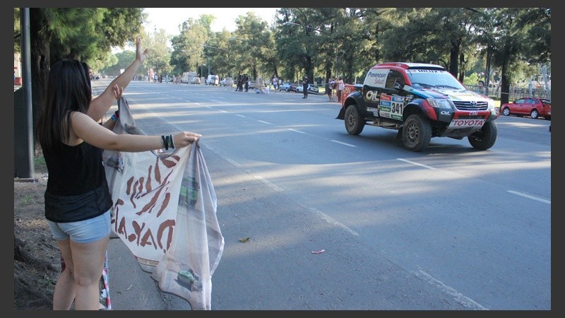 Una joven agita una bandera del Dakar para despedir a los participantes.