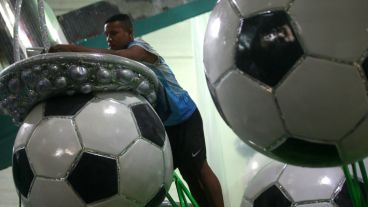 Un hombre trabaja sobre unos balones enormes de fútbol.