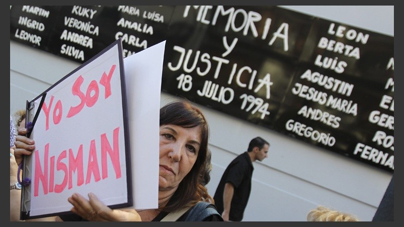 Una mujer muestra un cartel en apoyo al fiscal fallecido.