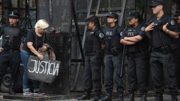 Una mujer coloca un cartel con la leyenda "Justicia" al lado del cordón policial.