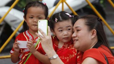 Una tailandesa de origen chino se toman una foto con dos niñas vestidas con el traje tradicional chino en la víspera de celebración.