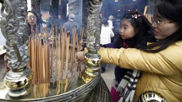 Una mujer y su hija encienden palos de incienso en el templo de Kanteibyo.