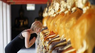 Una turista británica hace una reverencia ante los budas dorados del templo Wat Po.