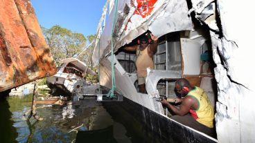Dos hombres realiza reparaciones en un bote golpeado por otra embarcación durante el paso del ciclón Pam.