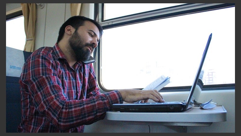 Un periodista trabaja arriba del tren. Importante: hay enchufes para cargar aparatos electrónicos.